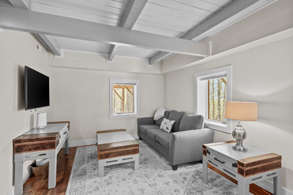 A cozy family room with a gray sofa, wooden coffee tables, a TV, and warm lighting. The space feels inviting and is perfect for relaxing after a day outdoors, watching movies, or hosting group gatherings.