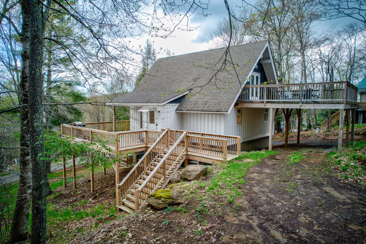 The image presents another angle of the wooden deck, showing the staircase leading into natural landscaping. The peaceful ambiance suggests a seamless transition from indoor comfort to outdoor adventure, reinforcing the home’s connection to its scenic location.