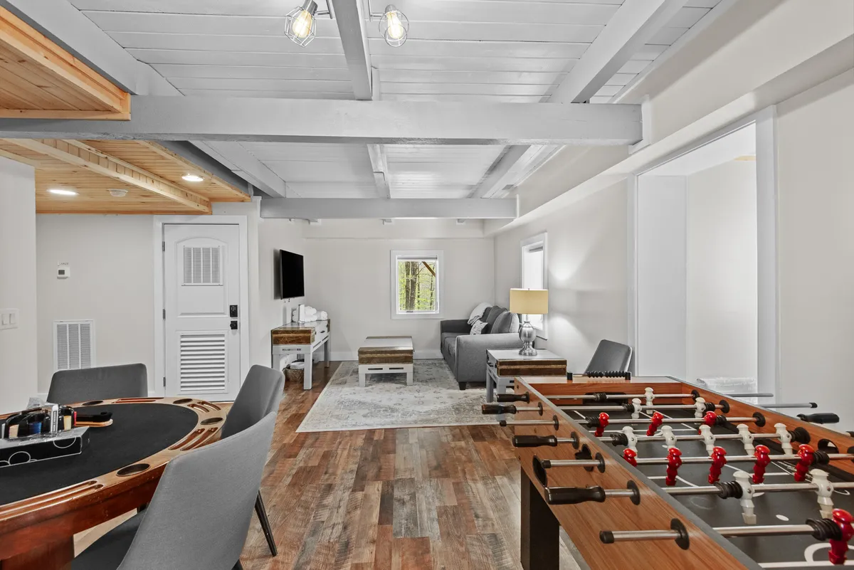 A playful family room featuring a foosball and gaming table, comfortable sofa area, and a window offering natural light. The setting is ideal for game nights, family bonding, or relaxing after a day of adventure.