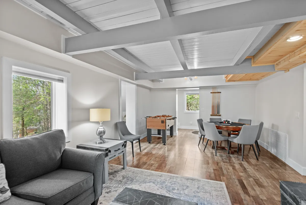 A comfortable interior scene featuring a sofa, foosball table, dining table, and a warm lamp, suggesting a space ideal for gathering, playing games, and relaxing with friends or family after winter adventures.